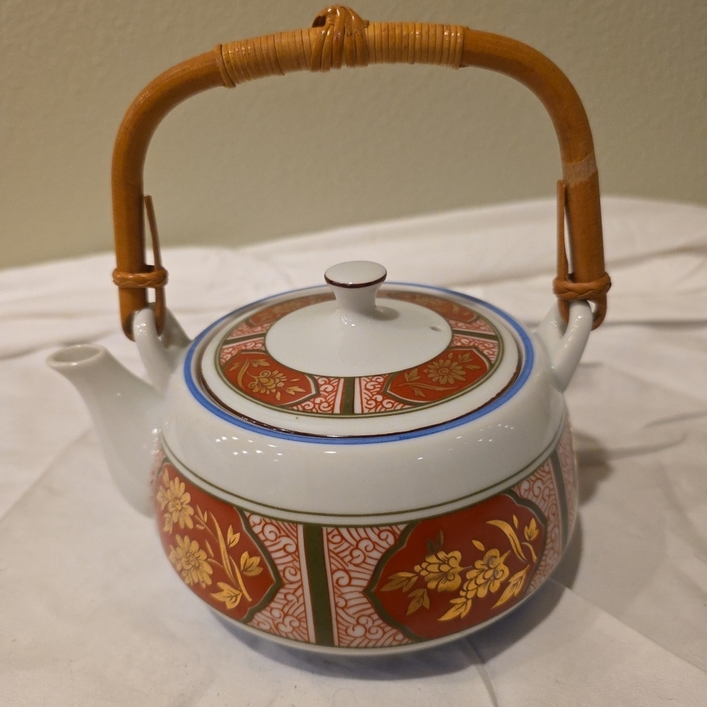 Vintage Japanese ceramic teapot with bamboo handle and floral motifs.